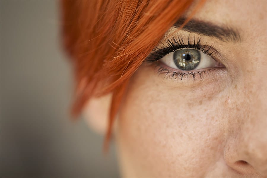 Mulher de cabelo ruivo com olheiras.