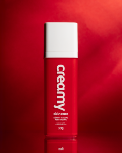 Retinal: tudo sobre o ativo que ajuda a suavizar rugas, linhas finas e perda de firmeza 1 Sérum Retinal da Creamy, em pé, em um fundo vermelho.