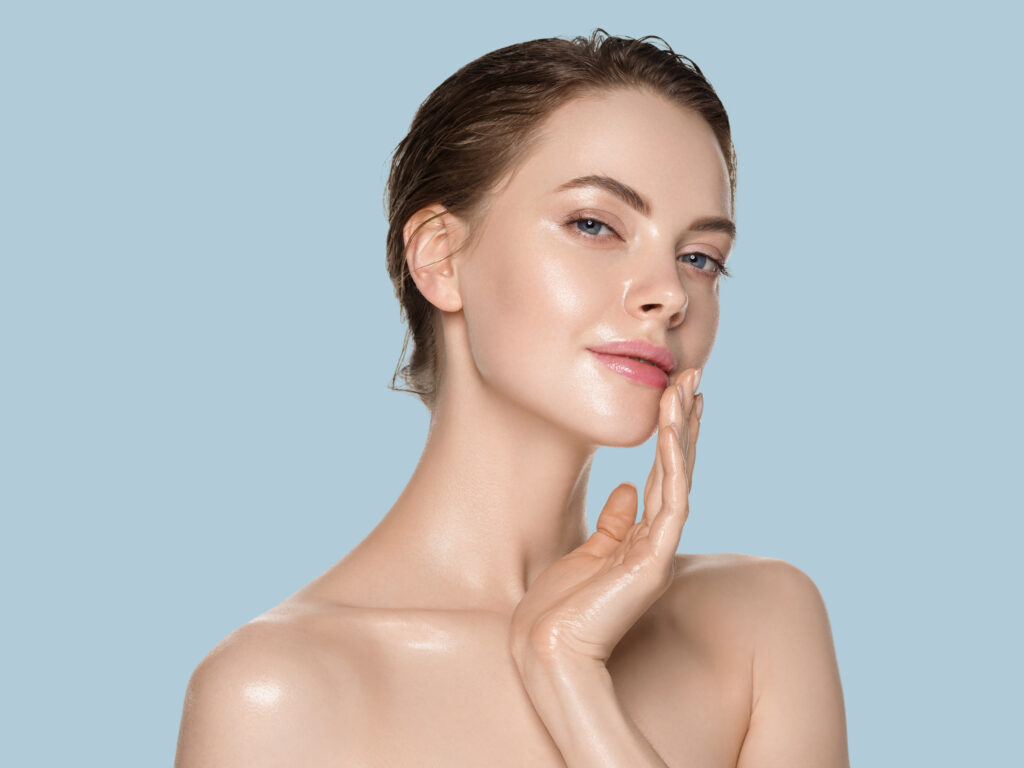 Glass Skin e Cloud Skin: entenda a diferença entre eles e como conquistar 1 Mulher com a mão no rosto, com a pele com efeito glass skin.